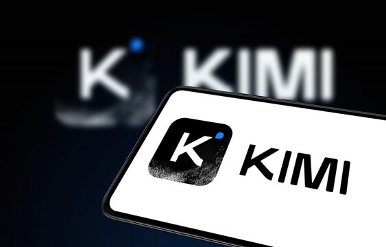 KIMI K3 chatbot model displayed on a smartphone screen in a bright modern workspace office setup