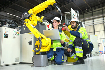 Fototapeta premium Workers use a robot arm to automate tasks in a factory environment during the day