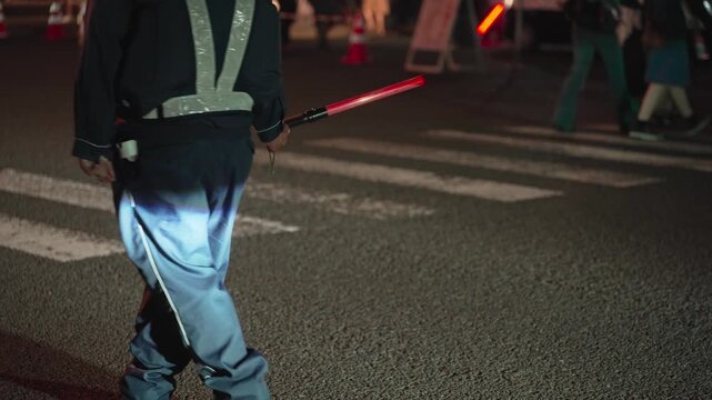 人が多い夜の交差点を警備する誘導員