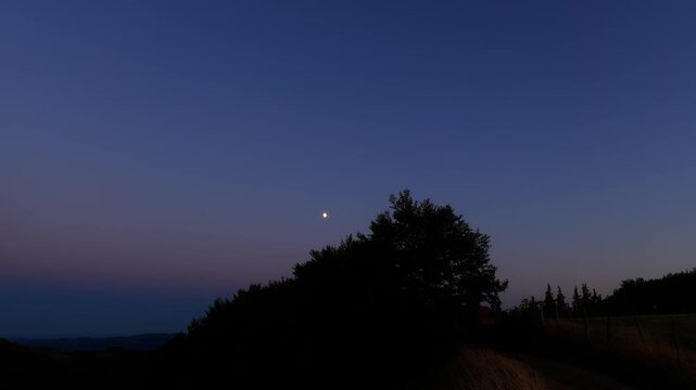 Moon on a twilight sky with landscape mountain silhouettes.