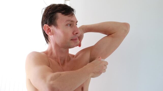 Homem passando desodorante nas axilas