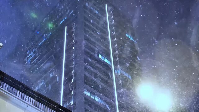 Modern High-Rise Building During Heavy Snowfall at Night