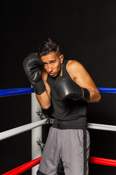 Focused Hispanic boxer in defensive stance ready for fight in dark gym
