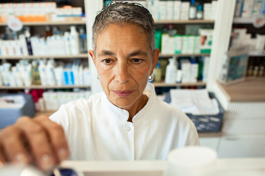 Mature female pharmacist selecting medication in pharmacy