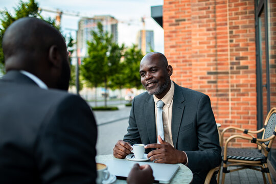 Two businessmen meeting over coffee at outdoor cafe
