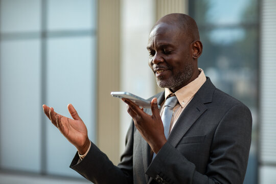 Businessman using voice assistant on smartphone outdoors