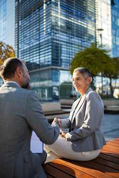 Senior business professionals shaking hands outside modern office building