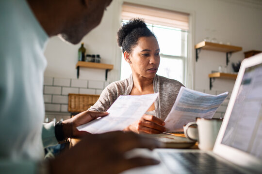 Couple reviewing household bills at home kitchen table