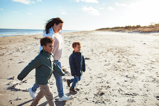 Mother and two boys walking on windy beach