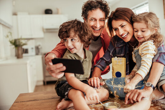 Happy family baking together and taking selfie in home kitchen