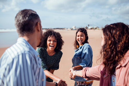Friends laughing and joining hands on the beach