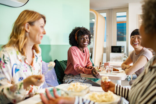 Diverse women laughing over lunch in office break room