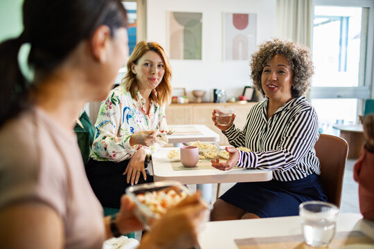 Coworkers eating lunch and talking in office breakroom