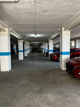 Cars parked in a half underground parking lot for cars with windows to the street.