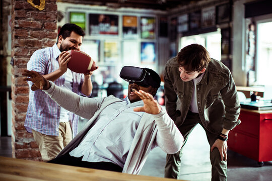 Young men playing virtual reality game in casual office lounge