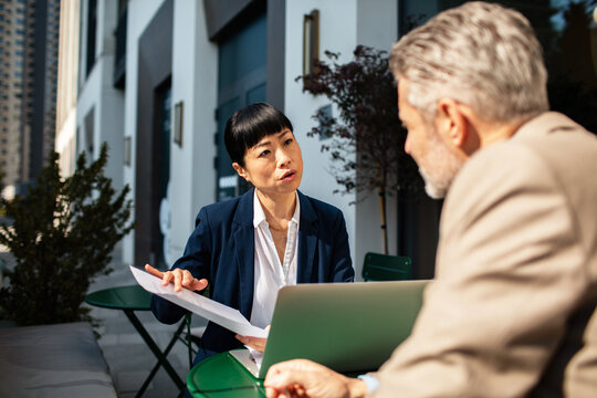 Business professionals discussing documents at outdoor cafe