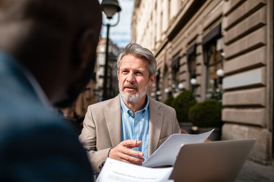 Senior businessman meeting with colleague at outdoor city cafe