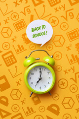 Fototapeta premium Green alarm clock on educational background with back to school message