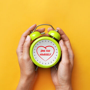 Hands holding alarm clock with meditation icon, time for yourself and self care concept