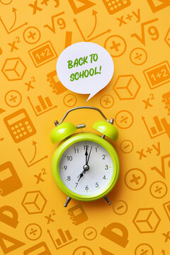 Green alarm clock on educational background with back to school message