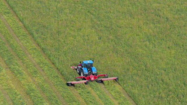 Aerial Drone View of Tractor Cutting Hay in Green Agricultural Field