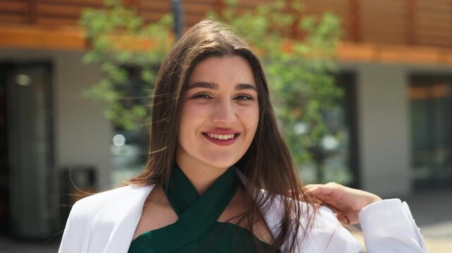 Beautiful young business woman touching her hair and smiling outdoors, slow motion