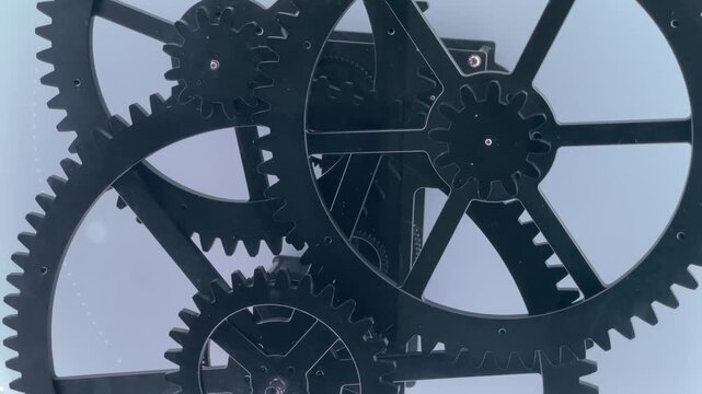 Three interlocking metal gears rotating at different speeds, transmitting mechanical motion through meshing teeth. Closeup view of movement, principles of power transmission in clean mechanical system