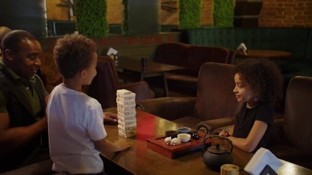 Black family building wooden block tower together