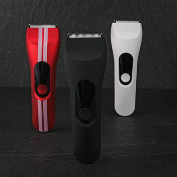 High-quality product photography of a sleek black cordless electric hair clipper and trimmer, placed on a premium dark slate stone texture background with shadow.