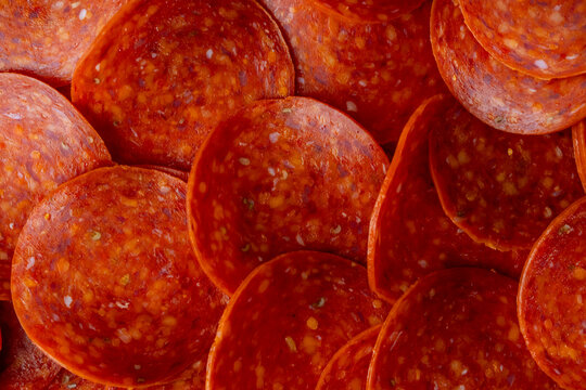 Closeup of uncooked pepperoni on a white marble surface 