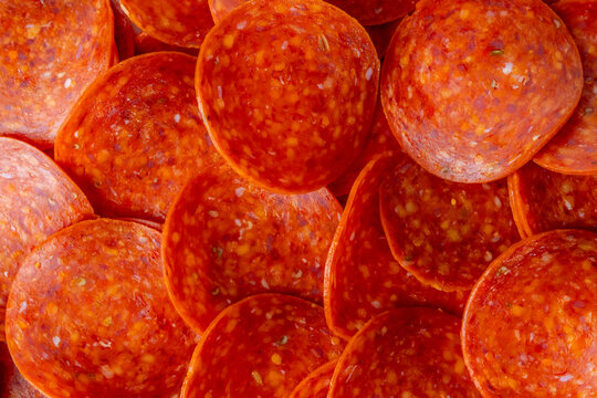 Closeup of uncooked pepperoni on a white marble surface 