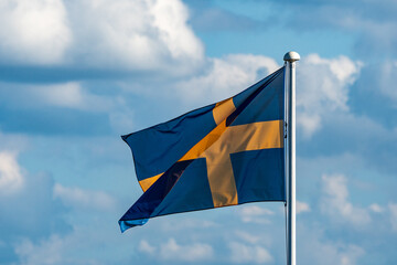 Fototapeta premium Swedish flag waving on flagpole against cloudy sky