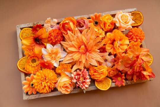 Tray with flowers in orange tones on a wooden tray with slices of dried orange