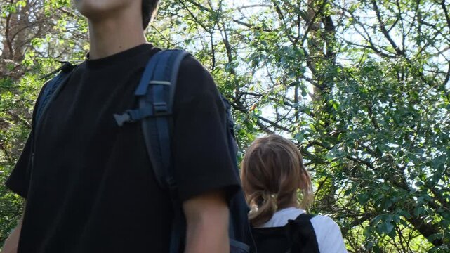Close up of two lost teenagers standing back to back in the forest, looking around with anxious expressions while trying to find their way. Panic, fear and child safety in the wilderness.