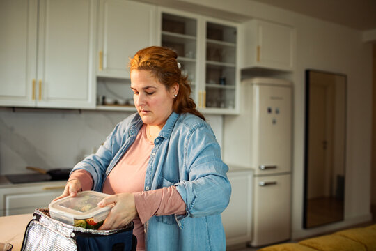 Woman packing meal prep lunch in home kitchen
