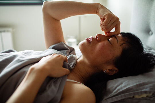 Woman with headache resting in bed at home