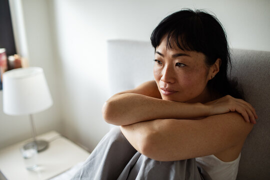 Thoughtful woman resting on bed at home