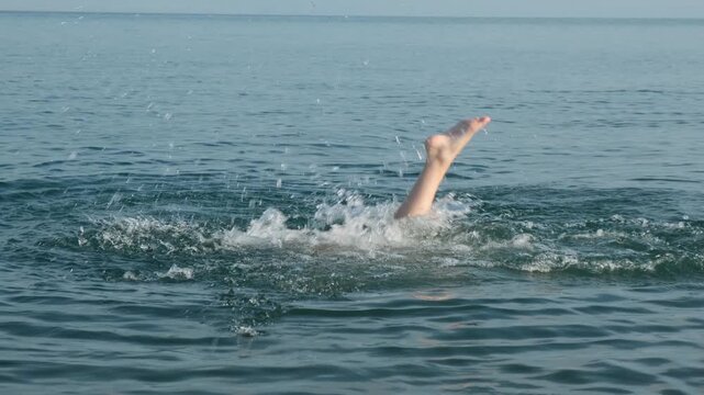 Happy girl aged 10 to 12 enjoys swimming in the sea, diving and doing underwater somersaults wearing a diving mask. Happy childhood, joyful youth and summer vacation.
