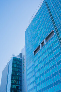 Two modern business skyscraper buildings made of glass and clear blue sky. Minimalistic abstract geometric pattern.Contemporary background, modern exterior, urban architecture