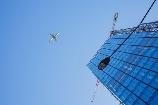 Civil aviation plane flying over the big city downtown with glass office buildings Contemporary background, modern exterior, urban architecture