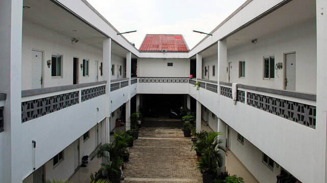 High angle symmetrical view of a modern two story apartment building courtyard with inner garden and paving block floor.