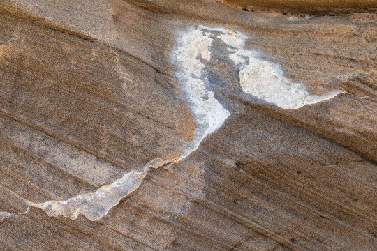 View of a textured rock formation with a prominent white mineral vein on the island of Santo Antao in Cruzinha, Ribeira Grande, Cabo Verde.