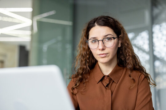 Young business employee sitting at work desk, focusing on a laptop, representing concentration, professionalism, and diligent work in a corporate environment