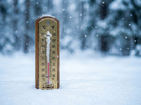 Outdoor thermometer showing freezing cold temperature standing in deep white snow during winter