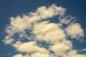 Obraz premium group of light wispy clouds scattered across blue summer sky during bright noon