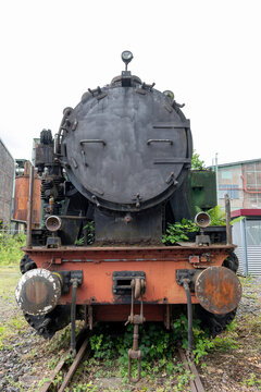 Photograph of an old, decommissioned locomotive at a steelworks site.