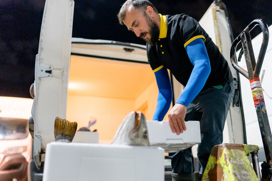 Fishmonger unload fish boxes from refrigerated delivery van