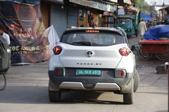 New delhi, india 11 april 2026 rear view of a white tata punch ev compact suv parked on a busy street in delhi, india, with a green electric vehicle license plate visible