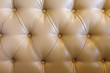 Obraz premium Beige tufted leather upholstery background with buttoned luxury furniture texture.