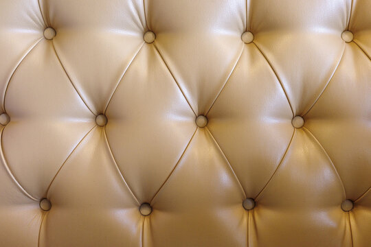Beige tufted leather upholstery background with buttoned luxury furniture texture.